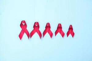 red ribbon composed of symbols of AIDS against HIV virus isolated on blue background photo