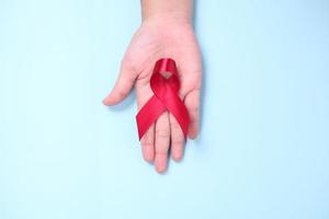 red ribbon in the palm of the symbol against HIV isolated on blue background photo