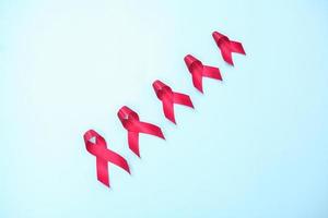 red ribbon composed of symbols of AIDS against HIV virus isolated on blue background photo