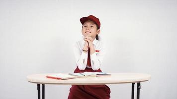 Niña de la escuela primaria asiática estudiando con pasión aislado sobre fondo blanco. foto