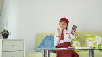 asian elementary school girl greeting to her phone screen at home studying photo