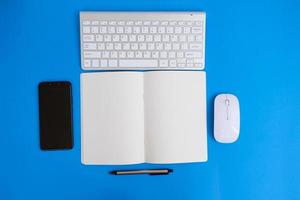 Blank notebook with pen is placed on an office desk table with computer tools and a range of materials. finance and banking background, flat lay, top view photo