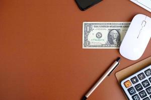 un cuaderno en blanco con bolígrafo se coloca en una mesa de oficina con herramientas informáticas y una variedad de materiales. antecedentes financieros y bancarios, endecha plana, vista superior foto