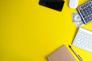 un cuaderno en blanco con bolígrafo se coloca en una mesa de oficina con herramientas informáticas y una variedad de materiales. antecedentes financieros y bancarios, endecha plana, vista superior foto