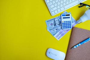 un cuaderno en blanco con un bolígrafo se sienta en una mesa de oficina rodeada de herramientas informáticas y una variedad de materiales. antecedentes en finanzas y banca, plano, vista superior foto