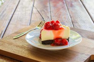 Cherry cheese pie cake in white plate and metal fork on wooden table. photo