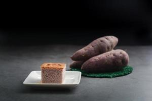 A square-cut of sweet potato cake on a white plate in the kitchen. Bakery and beverage concept. photo