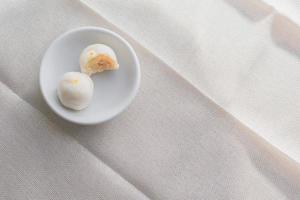 Puff moon cake with sweet mung bean and salt egg yolk in white bowl on table with copy space for your text. photo