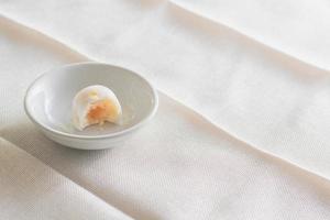 Puff moon cake with sweet mung bean and salt egg yolk in white bowl on table with copy space for your text. photo