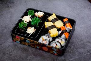 Set of variety sushi, Tamagoyaki, crabsticks sushi and maki in bento box served with soy sauce and wasabi. Delicious japanese food. photo