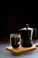 Espresso or black coffee and moka pot on wooden chopping board and dark table. Benefit of coffee concept.