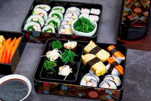 Set of variety sushi, Tamagoyaki, crabsticks sushi and maki in bento box served with soy sauce and wasabi. Delicious japanese food. photo