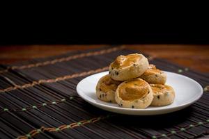 Cashew nut and black seasame cookies on white dish and wooden on black background.Copy space for your text. photo