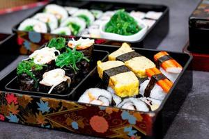 Set of variety sushi, Tamagoyaki, crabsticks sushi and maki in bento box served with soy sauce and wasabi. Delicious japanese food. photo