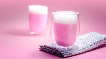 concepto de bebida de verano. leche rosa fresa con leche espumosa en vidrio transparente sobre fondo rosa. foto