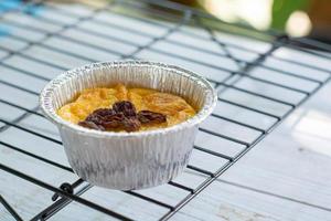 Bread pudding with black rasins in round foil cup on wooden tray. Delicious custard for coffee times. photo