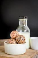 Healthy snack. Energy ball with date plum, black and white sesame, chia and rasin in ceramic bowl on wooden table. Vegan vegetarian. photo