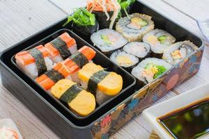 Set of variety sushi, Tamagoyaki, crabsticks sushi and maki in bento box served with soy sauce and wasabi. Delicious japanese food. photo