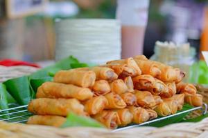 Delicious group of crispy spring roll on banana leave sell in local market of Thailand. Deep fries chinese snack. photo