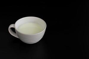 Side view of white cup of milk on black background with copy space. High protein and calcium. Healty beverage. photo