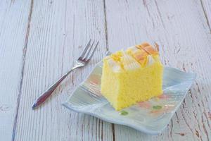 Piece of vanilla chiffon coconut cake on square plate on wooden table. Delicious small bakery for coffee and tea times. Copyspace for your text. photo