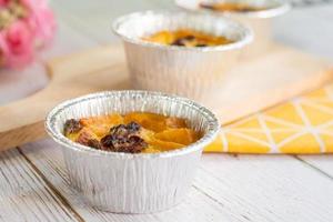 Bread pudding with black rasins in round foil cup on wooden tray. Delicious custard for coffee times. photo