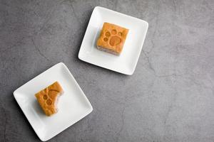 vista superior de un corte cuadrado de pastel de camote en un plato blanco en la cocina. concepto de panadería y bebidas. foto