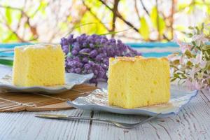 Piece of vanilla chiffon coconut cake on square plate on wooden table. Delicious small bakery for coffee and tea times. photo