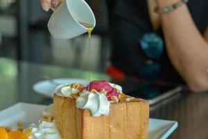 Pour honey on Honey toast with red homemade ice cream and whipping cream topping serve with orange in cafe and restaurant. photo