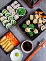 Set of variety sushi, Tamagoyaki, crabsticks sushi and maki in bento box served with soy sauce and wasabi. Delicious japanese food. Top view. photo