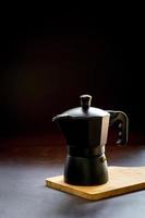 Espresso or black coffee and moka pot on wooden chopping board and dark table. Benefit of coffee concept.