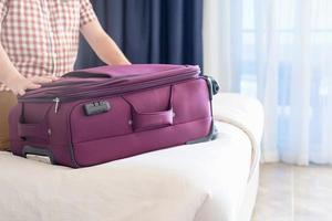 Handsome Caucasian young man packing his suitcase for travel photo