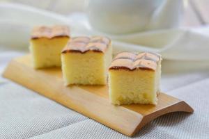 corte de cubo de pastel de mantequilla en bandeja de madera y mesa para servir en fiesta. delicioso postre comer con té y café por la mañana. foto