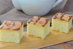 corte de cubo de pastel de mantequilla en bandeja de madera y mesa para servir en fiesta. delicioso postre comer con té y café por la mañana. foto