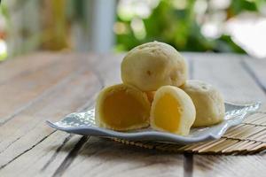 Thai style Mochi with Mung Bean stack on white plate  and wooden table with copy space for your text. Thai sweet dessert. Green bokeh background. photo