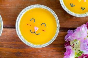 vista superior pastel de naranja mínimo con sonrisa de crema de mantequilla en una taza de aluminio sobre una mesa de madera. deliciosa panadería en tiempos de café y té foto