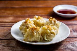 Chinese Steamed Dumpling, Shumai on white dish served with soy sauce on wooden table. Delicious Dimsum pork. photo