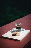 Espresso or black coffee served with butter and vanilla cookies on wooden table with green natural background. Energy drink in the morning concept. photo