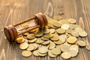 Vintage hourglass or sandglass and coin on wooden table. Saving time and money concept photo