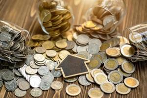 Wooden house model and coin stack on wooden table. Money savings for the home concept photo