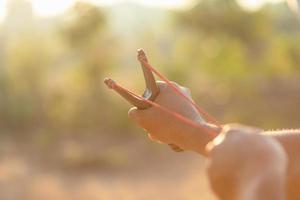 Man playing slingshot or catapult in morning time with sunlight effect photo