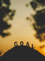 Silhouette of word GOAL on top of the hill in sunset time photo