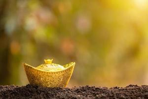 lingotes de oro para la decoración del año nuevo chino en la parte superior de la pila de suelo en el fondo borroso del jardín foto