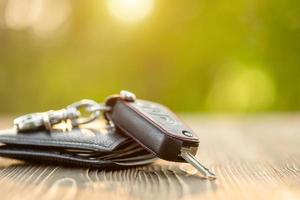 llaves de coche nuevas con billetera de cuero negro sobre mesa de madera. concepto de compra o alquiler de coches foto