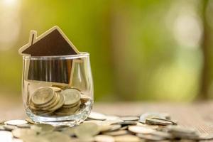 Wooden house model and coin stack on wooden table. Money savings for the home concept photo