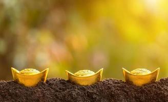 lingotes de oro para la decoración del año nuevo chino en la parte superior de la pila de suelo en el fondo borroso del jardín foto