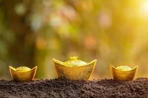 lingotes de oro para la decoración del año nuevo chino en la parte superior de la pila de suelo en el fondo borroso del jardín foto