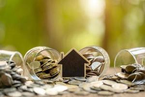 Wooden house model and coin stack on wooden table. Money savings for the home concept photo