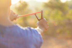 Man playing slingshot or catapult in morning time with sunlight effect photo