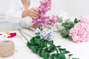 young women business owner florist making or Arranging Artificial flowers vest in her shop, craft and hand made concept photo